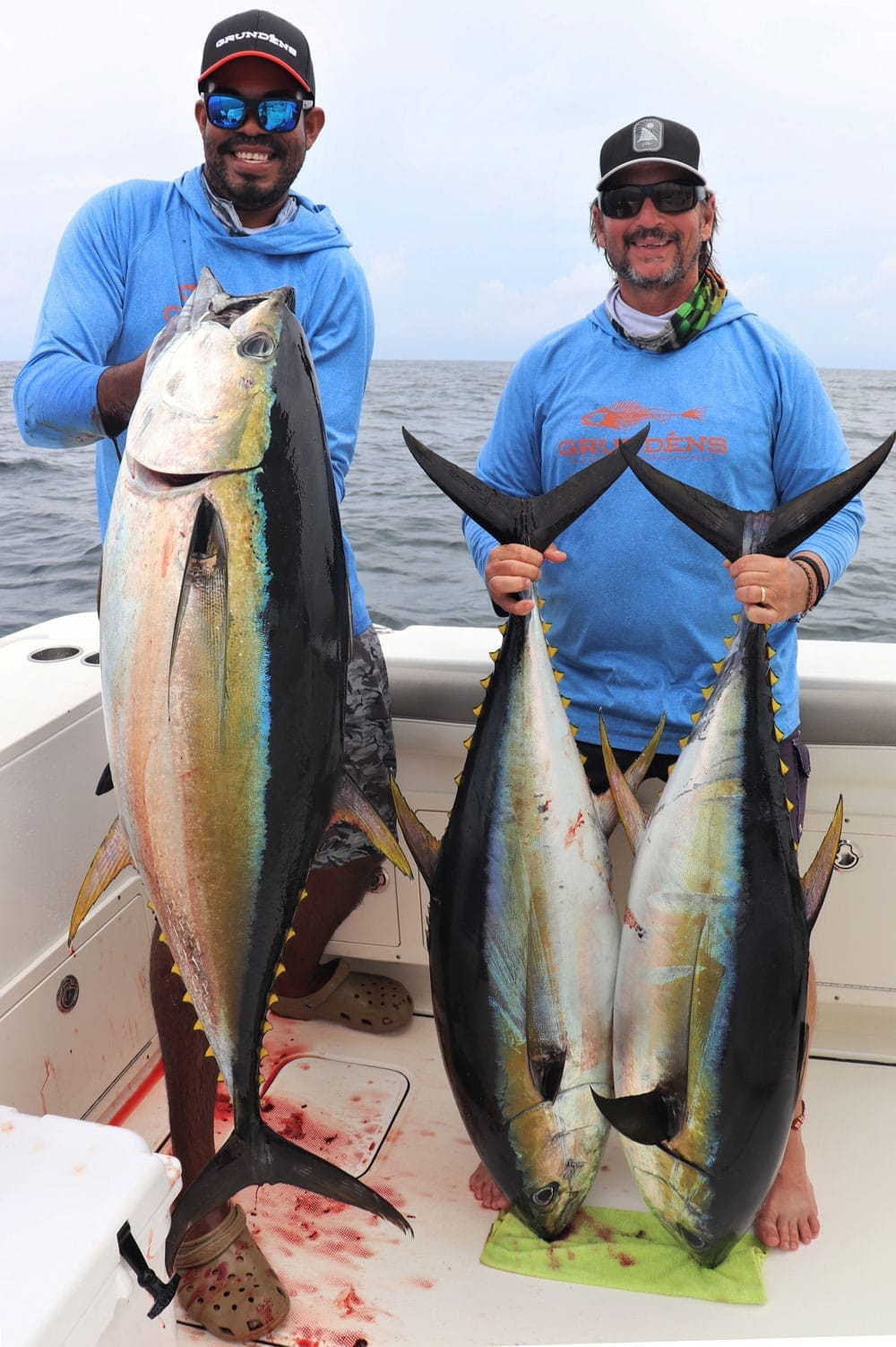 Mate and angler Jay holding yellowfin tunas aboard the boat